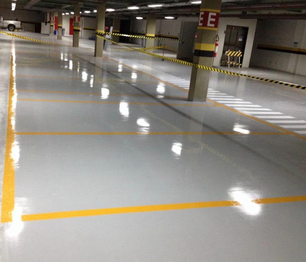 Estacionamento coberto com piso epóxi cinza e demarcação amarela de vagas e circulação