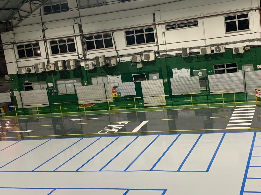 Piso industrial brilhante com faixas amarelas de demarcação em centro de distribuição