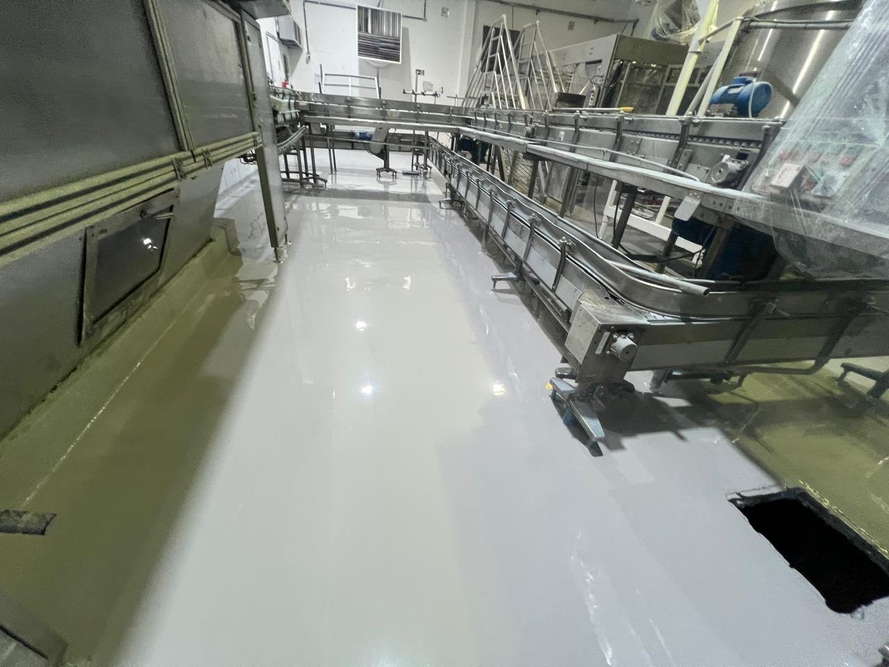 Piso epóxi industrial aplicado em estacionamento com faixa azul de circulação