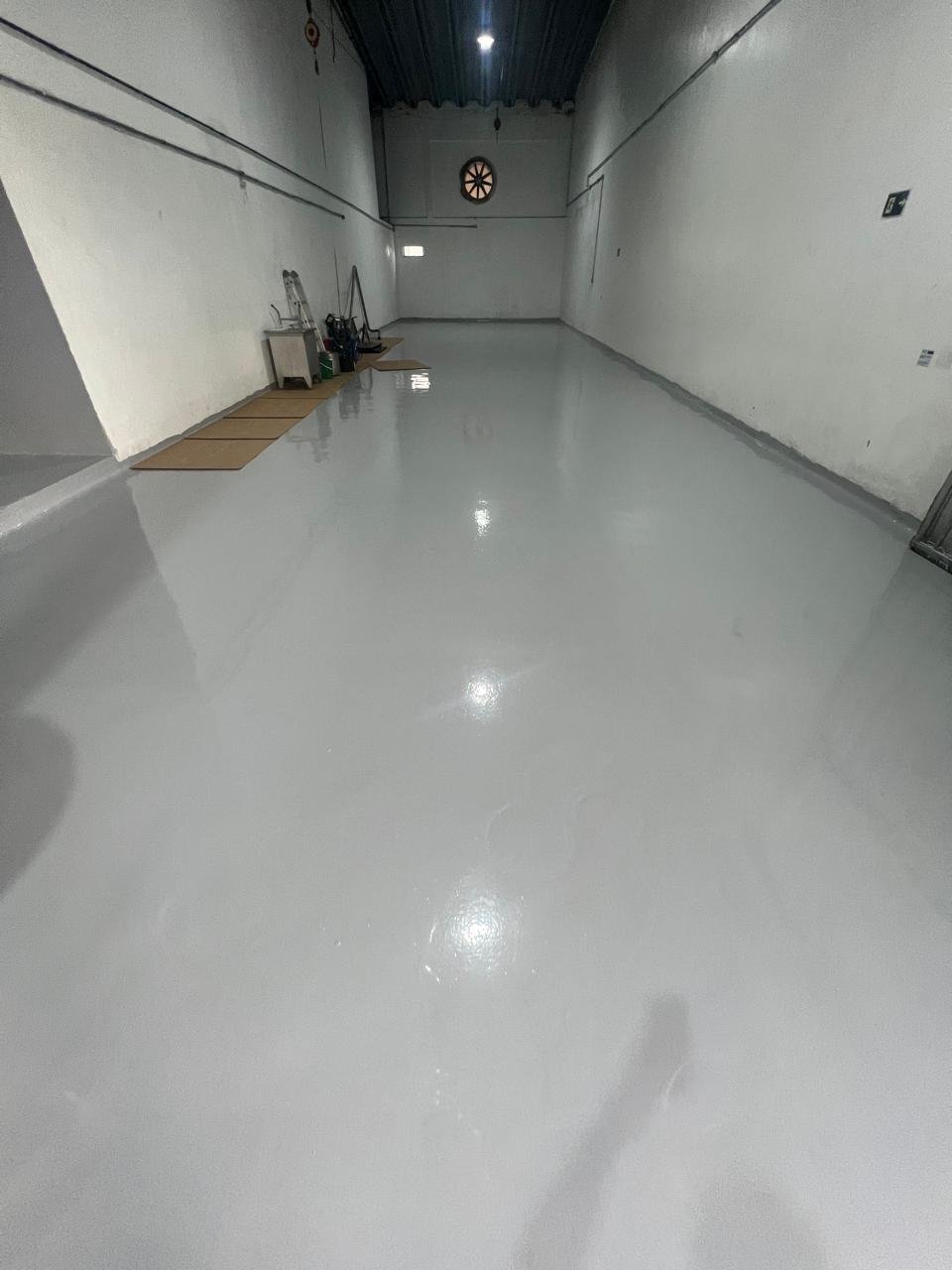 Piso epóxi industrial cinza aplicado em área de máquinas com acabamento brilhante